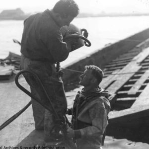 Le sergent Joseph B. Piccardella s’apprête à mettre le casque au plongeur Edgar B. Moore.